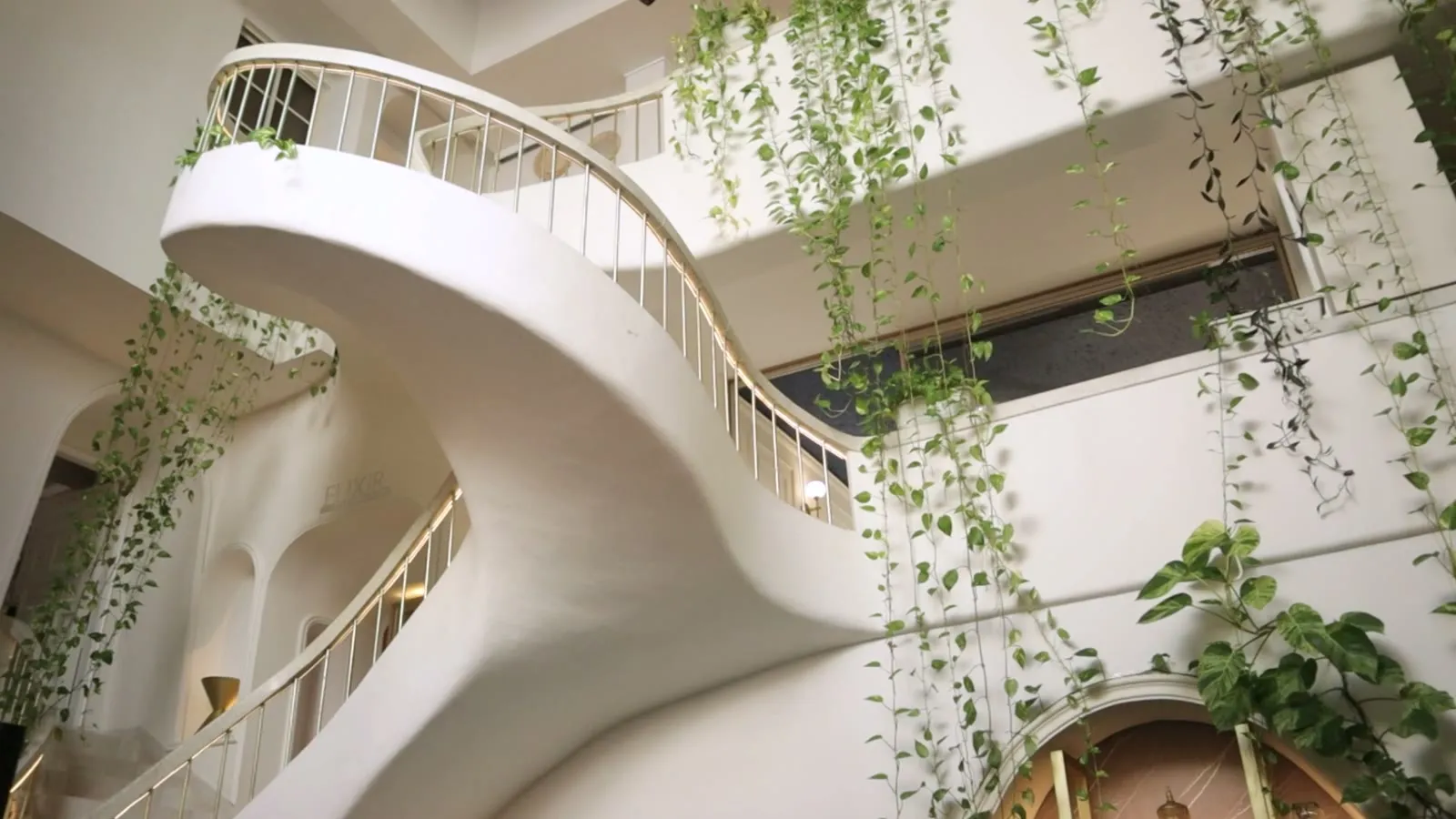 Atrio de Casa Elixir con escalera escultórica y jardines colgantes